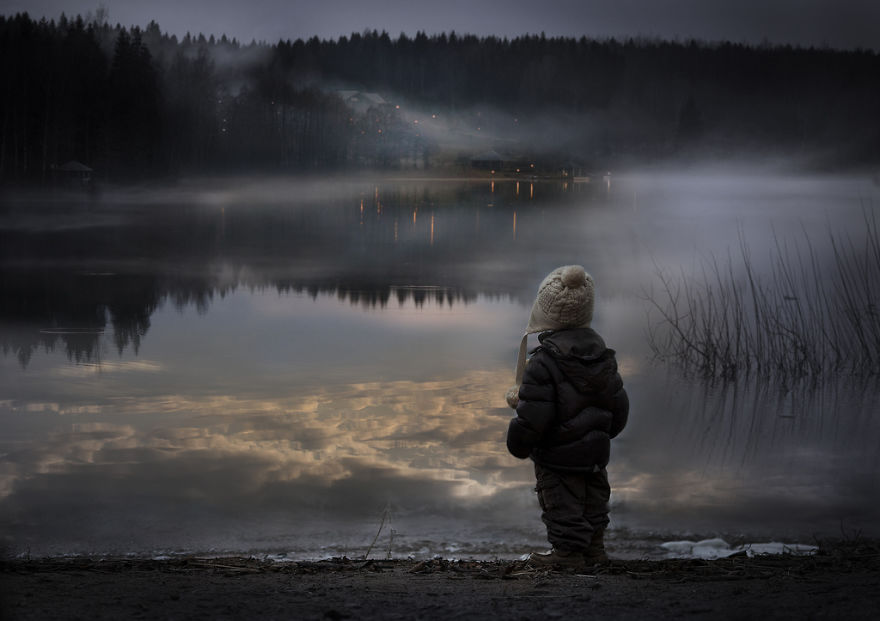 Child in winter clothing gazing at a misty lake on a Russian farm during twilight. Child in winter clothing gazing at a misty lake on a Russian farm during twilight.