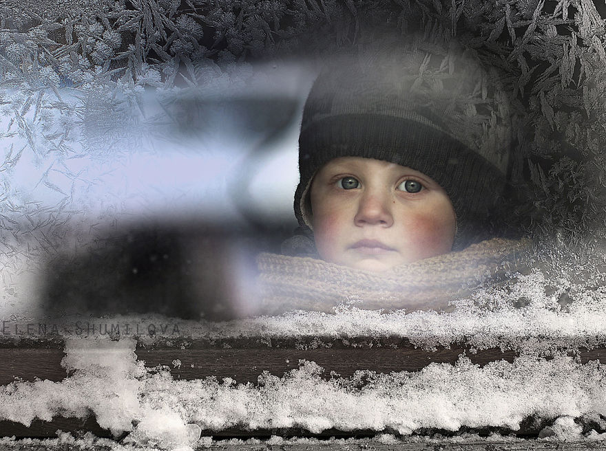 Child in winter clothing gazes through frosty window on Russian farm, creating a magical scene. Child in winter clothing gazes through frosty window on Russian farm, creating a magical scene.