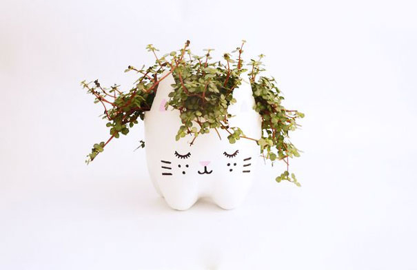 Recycled plastic bottle planter shaped like a cat, filled with green plants. Recycled plastic bottle planter shaped like a cat, filled with green plants.