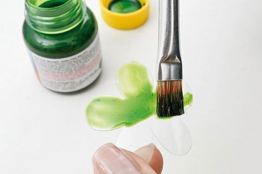 Painting a recycled plastic bottle piece with green paint and brush. Painting a recycled plastic bottle piece with green paint and brush.
