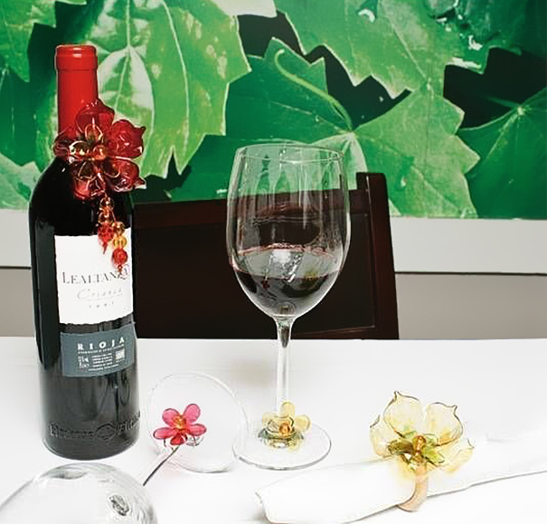 Red wine bottle and glass with decorative flowers made from recycled plastic bottles on a white tablecloth. Red wine bottle and glass with decorative flowers made from recycled plastic bottles on a white tablecloth.