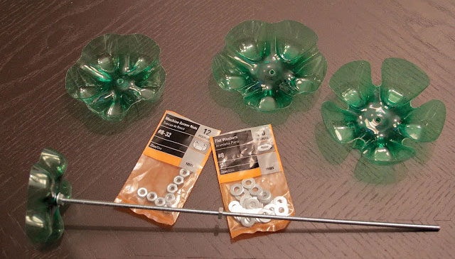 Recycled plastic bottles transformed into decorative flowers with metal washers and rods on a wooden table. Recycled plastic bottles transformed into decorative flowers with metal washers and rods on a wooden table.