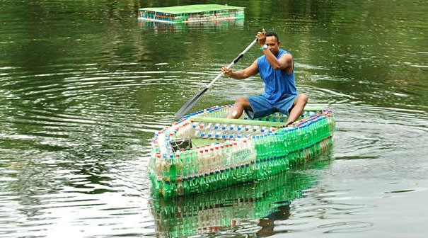 Man paddling a boat made from recycled plastic bottles on a lake. Man paddling a boat made from recycled plastic bottles on a lake.