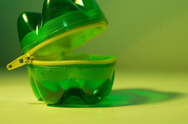 Creative recycled plastic bottle made into a green zippered container on a light surface. Creative recycled plastic bottle made into a green zippered container on a light surface.