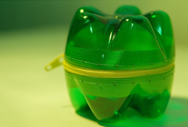 Recycled plastic bottle transformed into a green storage container with a yellow zipper. Recycled plastic bottle transformed into a green storage container with a yellow zipper.