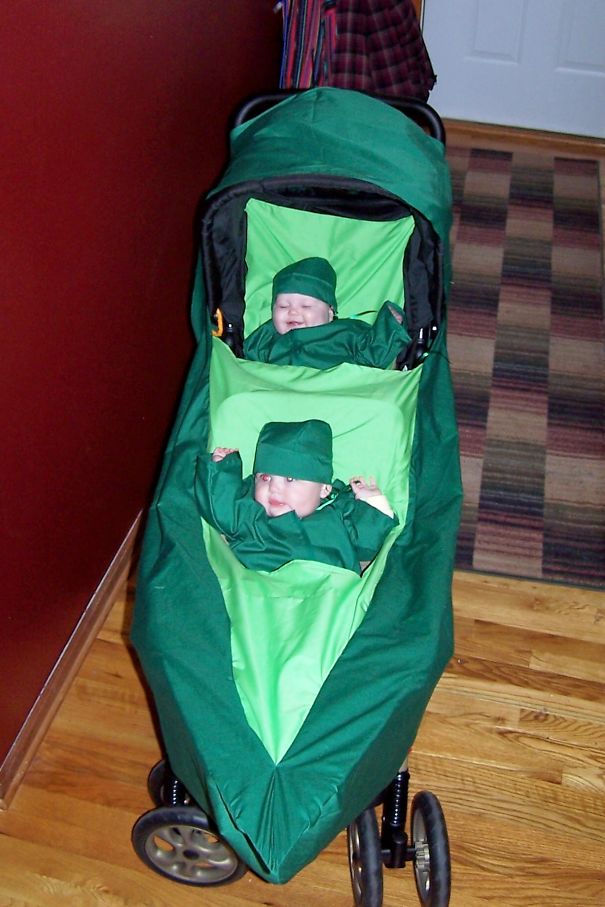 Two babies dressed in matching green Halloween costumes sitting in a stroller for children's Halloween costume ideas