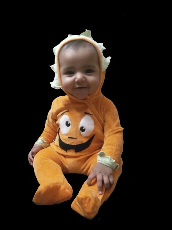 Baby wearing a cute orange Halloween costume with a smiling pumpkin face, perfect for children's Halloween costume ideas.