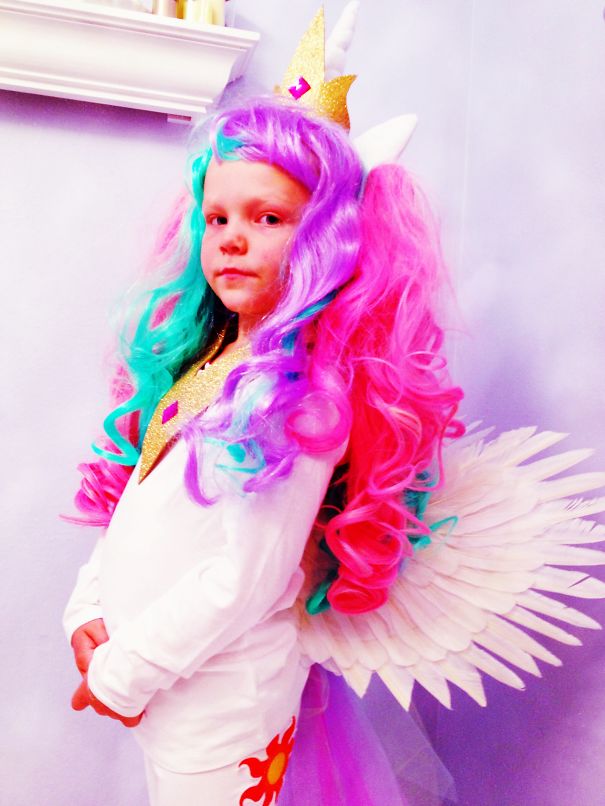 Child dressed in colorful unicorn costume with wings and a crown, a creative children's Halloween costume idea.