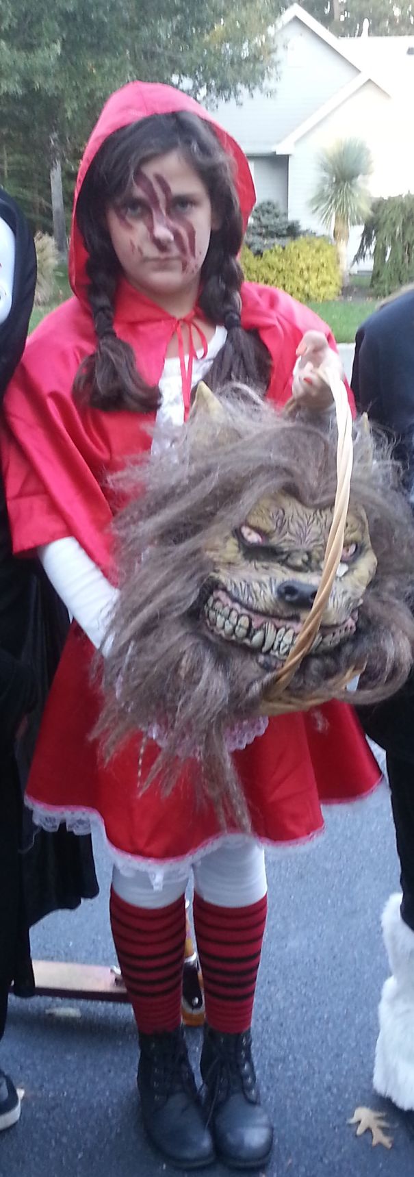 Child in Halloween costume holding a creepy werewolf mask, showcasing unique children's Halloween costume ideas outdoors.