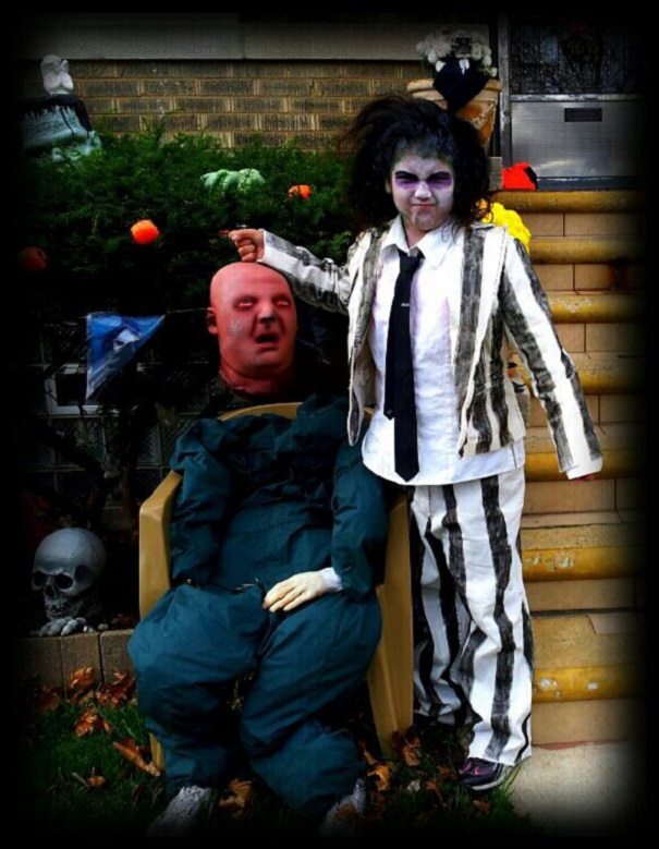 Child in spooky children's Halloween costume ideas outfit standing next to a Halloween decoration on porch steps.