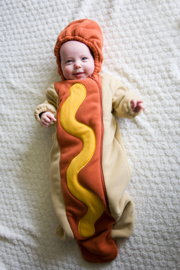 Baby lying down wearing a hot dog Halloween costume, a cute idea from children's Halloween costume ideas.