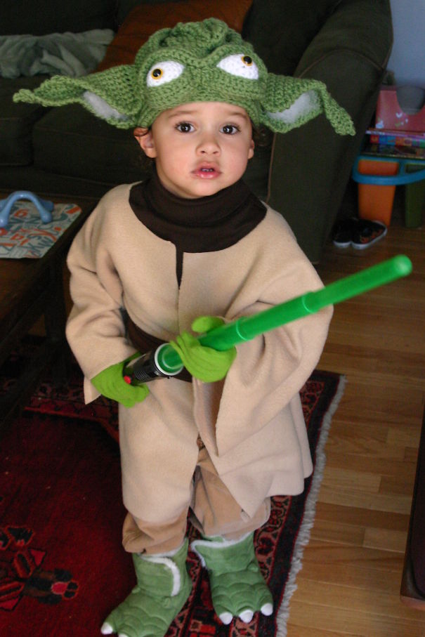 Child dressed in a creative Halloween costume holding a green lightsaber, perfect for children's Halloween costume ideas.
