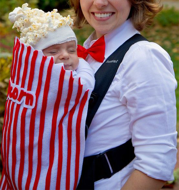 Baby dressed as a popcorn bag in a creative children's Halloween costume idea carried by a smiling adult.