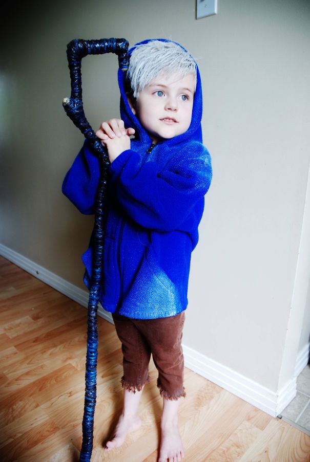 Child dressed in a blue hoodie holding a staff, showcasing a creative children's Halloween costume idea indoors.