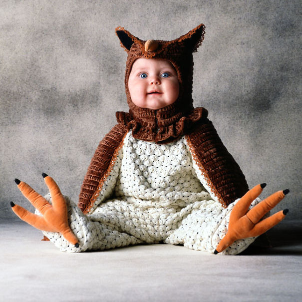 Baby dressed in a detailed bird costume sitting against a plain background, showcasing creative children's Halloween costume ideas.