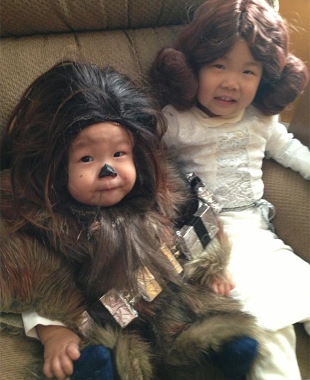 Two children sitting on a couch dressed in creative children's Halloween costume ideas, one as Chewbacca and another as Princess Leia.