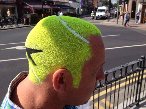 Man with a crazy haircut styled like a bright green tennis ball, standing on a city street.