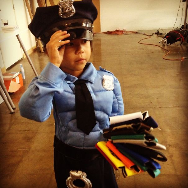 Child dressed as a police officer costume holding colorful fabric pieces for children's Halloween costume ideas.