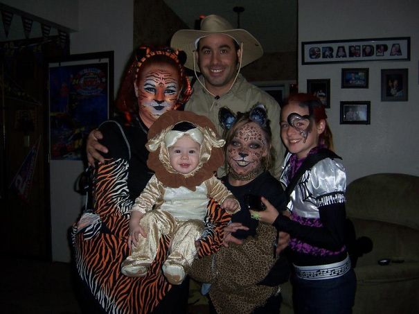 Family dressed in creative children's Halloween costume ideas including tiger, lion, leopard, and themed outfits inside a home.