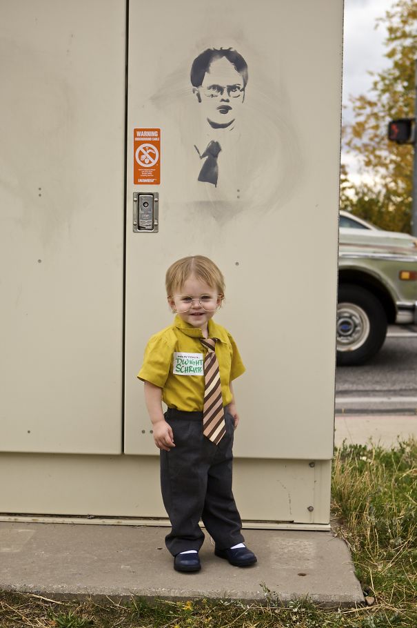 Toddler dressed in creative children's Halloween costume with glasses and tie standing outdoors near a utility box.
