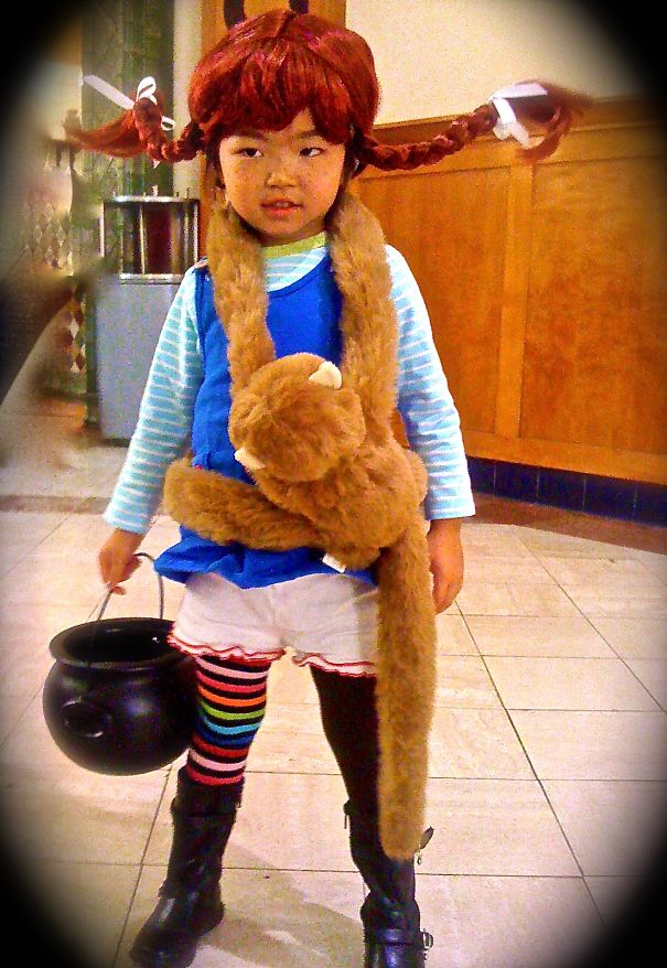 Child wearing colorful Halloween costume with striped leggings and carrying a black bucket for trick-or-treat in children's Halloween costume ideas.
