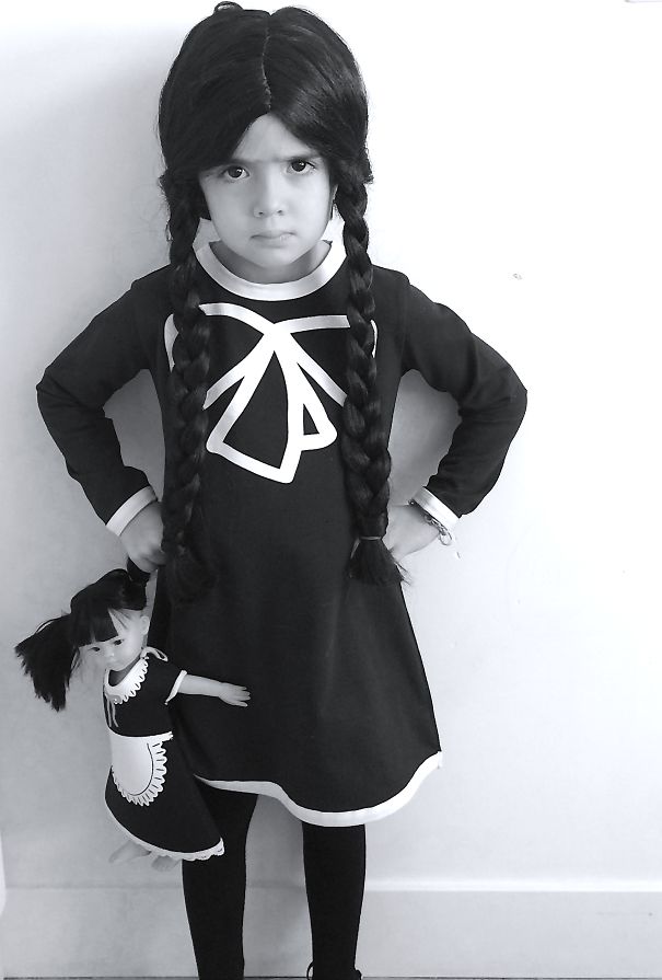 Child in Halloween costume standing with matching doll, showcasing creative children's Halloween costume ideas.