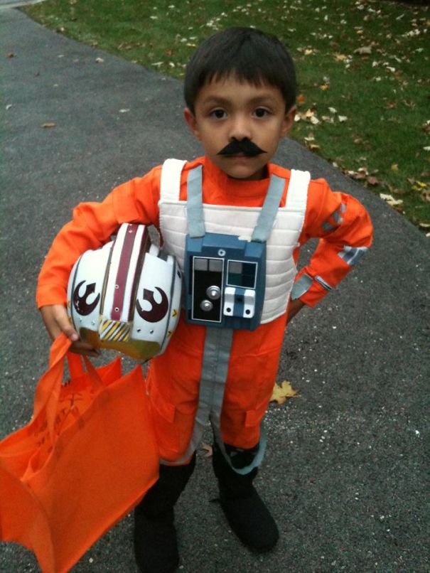 Child dressed in a Halloween costume holding a helmet and orange bag, showcasing creative children's Halloween costume ideas.