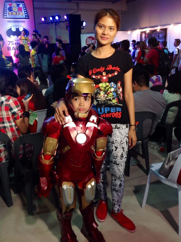 Young child dressed in Iron Man costume with adult nearby at a crowded event showcasing children's Halloween costume ideas.