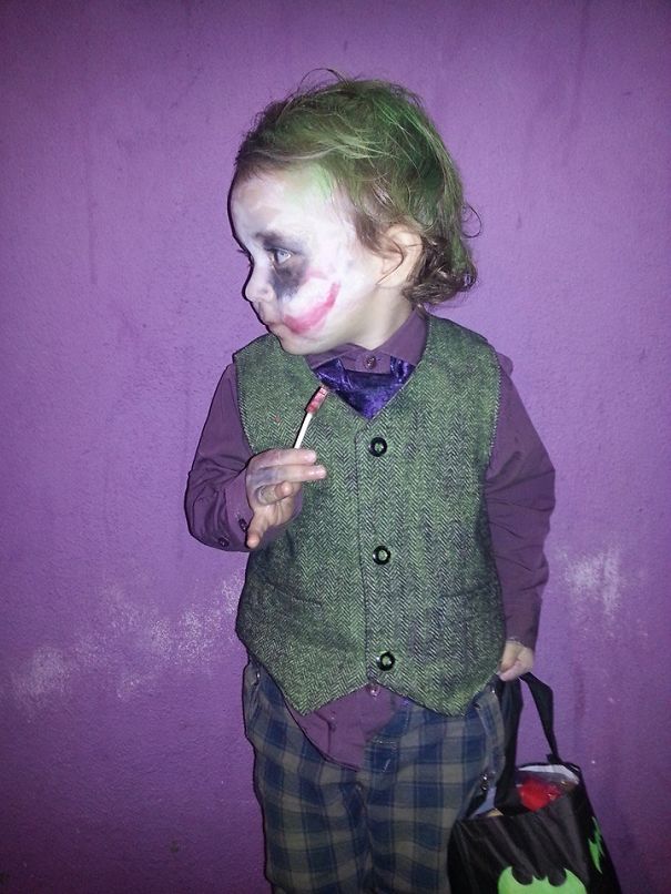 Child in a Halloween costume with face paint, green hair, vest, and plaid pants holding a trick-or-treat bag for children's Halloween costume ideas.