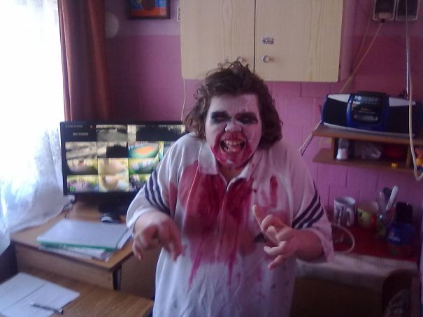 Child in a spooky Halloween costume with face paint and fake blood posing indoors for children's Halloween costume ideas.