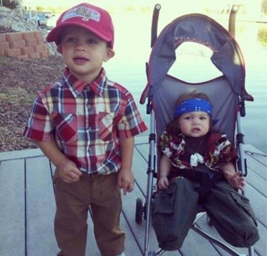 Two young children in Halloween costume ideas, one standing in a plaid shirt and hat, the other sitting in a stroller with a bandana.