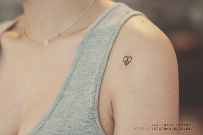 Minimalistic tattoo by Seoeon on a woman's shoulder, featuring a small heart design in a discreet style. Minimalistic tattoo by Seoeon on a woman's shoulder, featuring a small heart design in a discreet style.