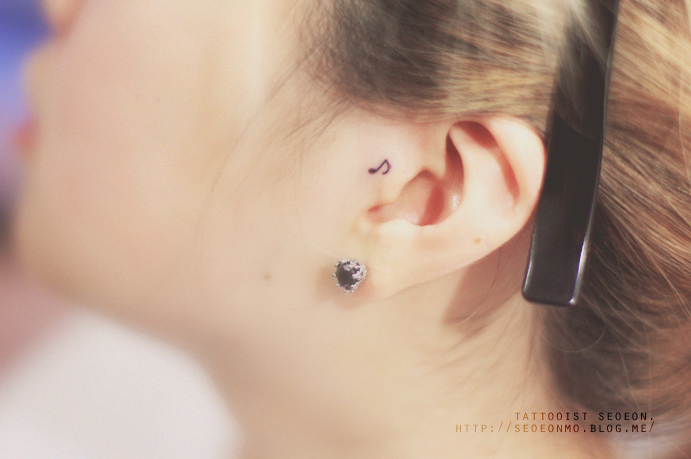 Minimalistic tattoo by Seoeon, a discreet musical note behind the ear, showcasing feminine elegance. Minimalistic tattoo by Seoeon, a discreet musical note behind the ear, showcasing feminine elegance.