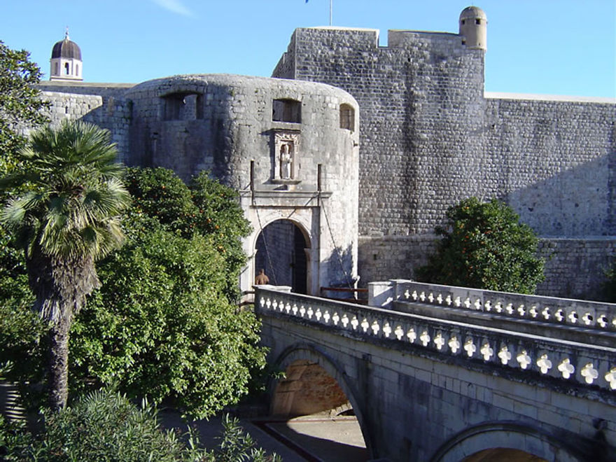 Stone bridge and ancient fortified gate surrounded by greenery, showcasing a mystical bridge that transports to another world.