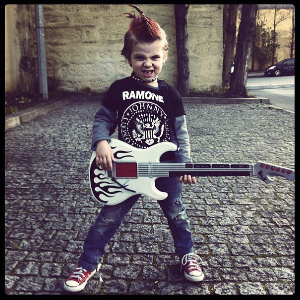 Child dressed in a punk rock costume holding a guitar outside, showcasing creative children's Halloween costume ideas.