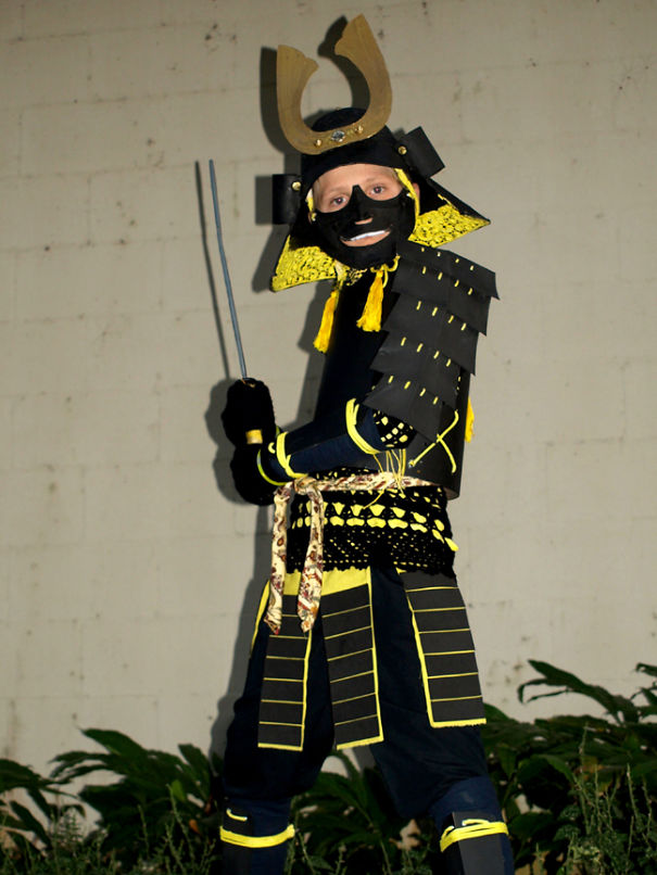 Child dressed in an elaborate samurai Halloween costume, posing with swords for children's Halloween costume ideas.