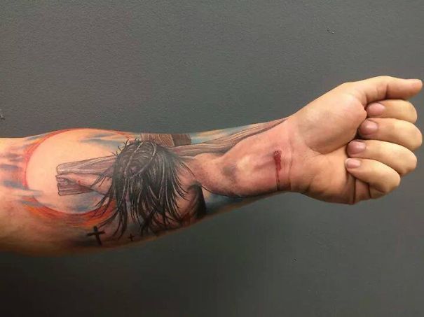 3D tattoo of Jesus on a cross on a man's forearm, creating a mind-twisting visual effect.