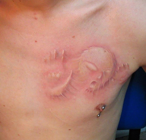 3D tattoo on chest depicting a face pressing against the skin, creating a mind-twisting illusion.