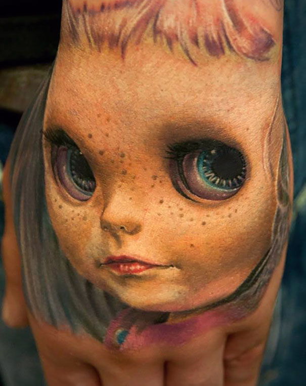 3D tattoo of a doll's face on a hand, showcasing intricate details and realistic effects.
