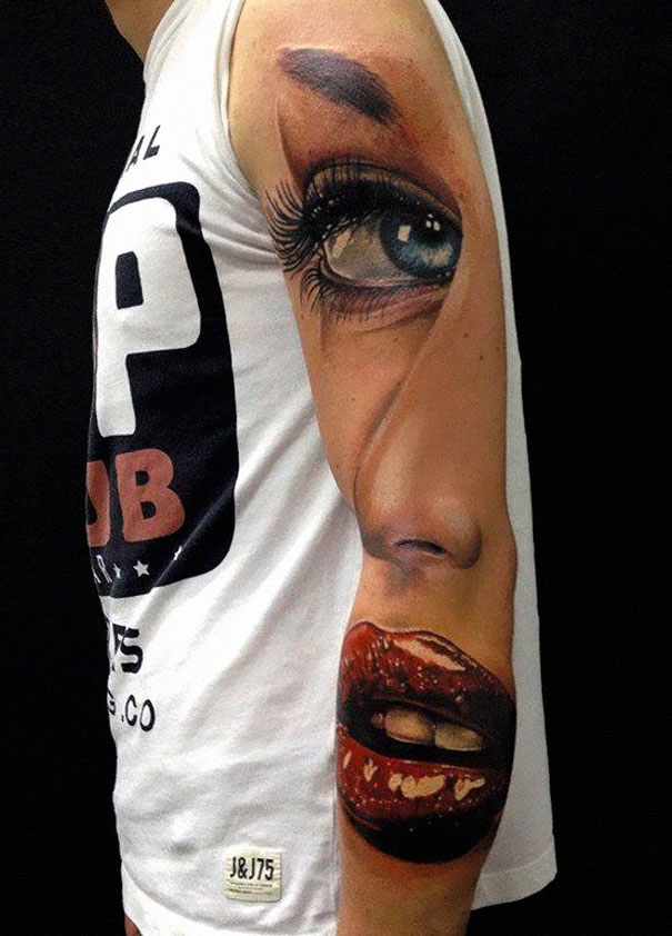 3D tattoo of a realistic face, including eye and lips, on a person's arm, creating a mind-twisting optical illusion.