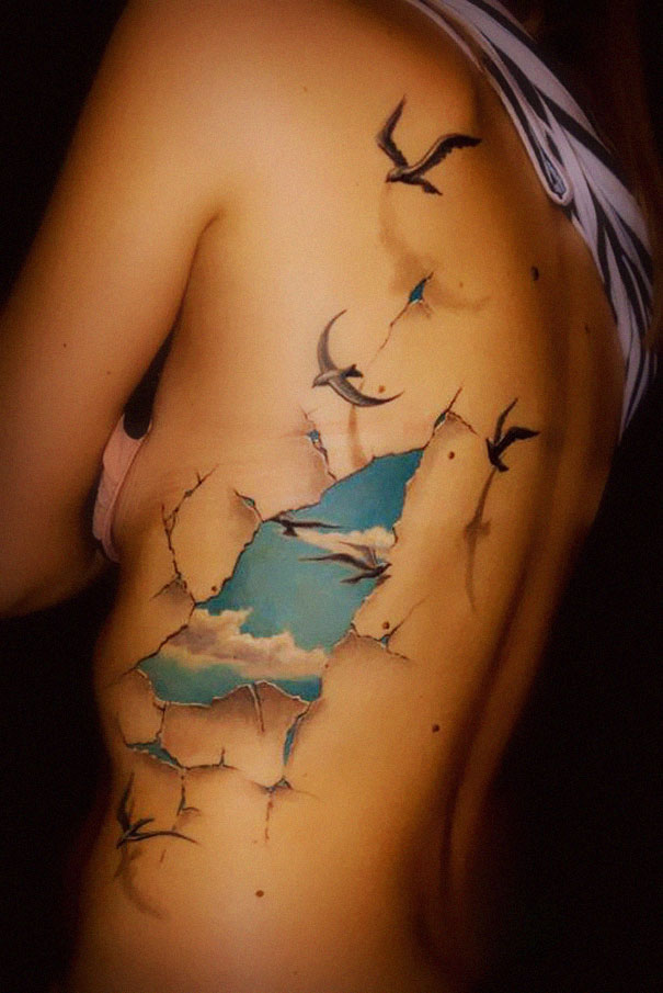 3D tattoo with a ripped skin effect revealing a sky and flying birds.