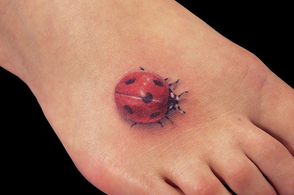 3D tattoo of a ladybug on a foot, showcasing incredible realism.