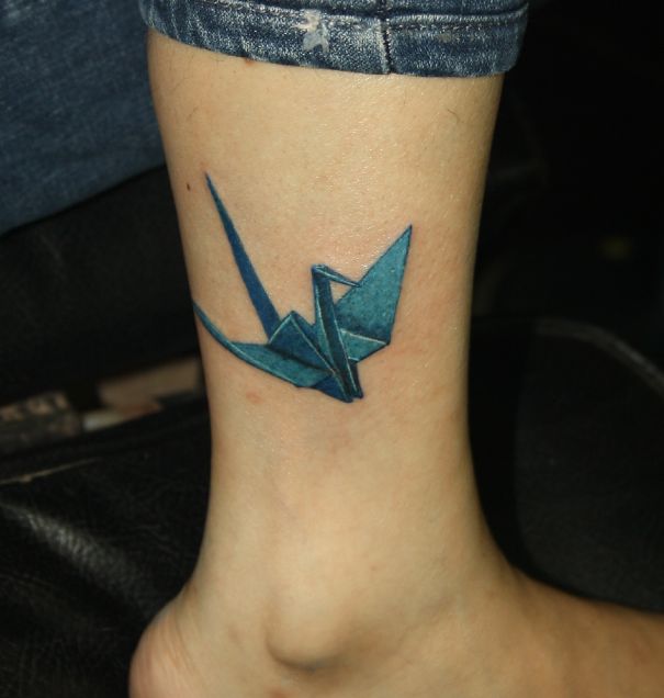 3D tattoo of a blue origami crane on an ankle, creating a realistic and mind-twisting effect.