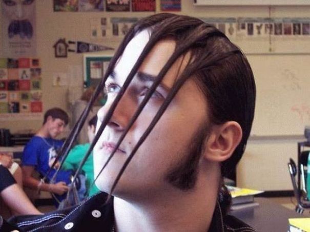 Unusual haircut with long, vertical strands framing a person's face in a classroom setting.