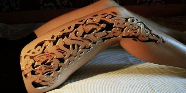 3D tattoo with intricate cutout design on a thigh, creating a striking illusion.