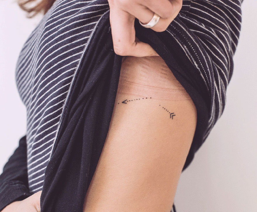 Minimalist tattoo of arrows on a person's side, created by an artist in exchange for lessons, books, or food. Minimalist tattoo of arrows on a person's side, created by an artist in exchange for lessons, books, or food.
