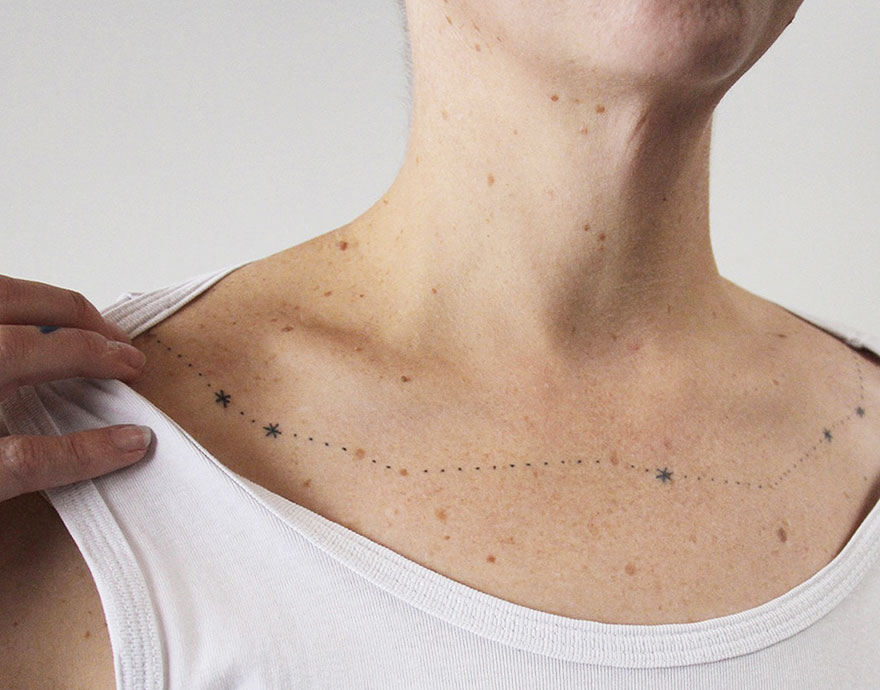 Minimalist tattoo of stars and dots on a person's collarbone, created by artist in exchange for food, lessons, or books.