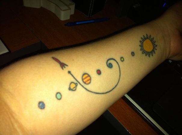 Colorful cosmic tattoo on arm featuring planets and sun, perfect for astronomy lovers.
