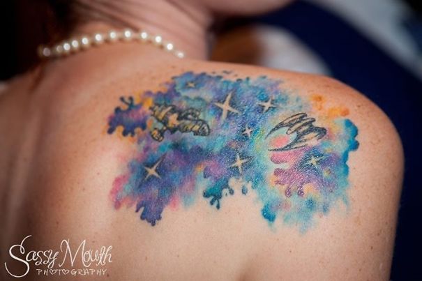 Colorful cosmic back tattoo featuring ships, stars, and galaxies for astronomy lovers.