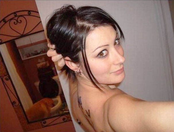 Woman taking a selfie with a mirror reflecting a hidden detail in the background.